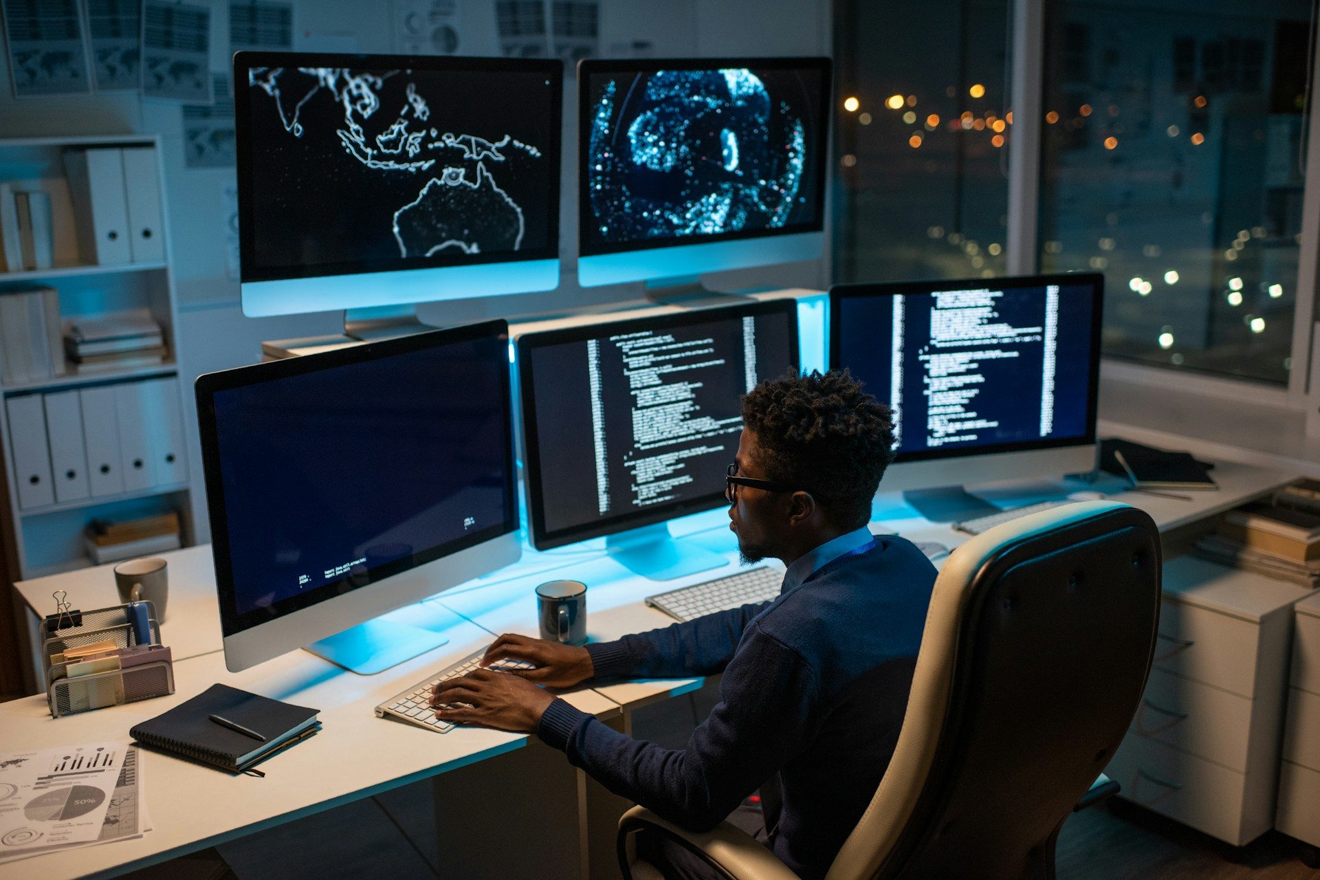 Un desarrollador trabajando entre paneles de agentes en vivo en una oficina de noche